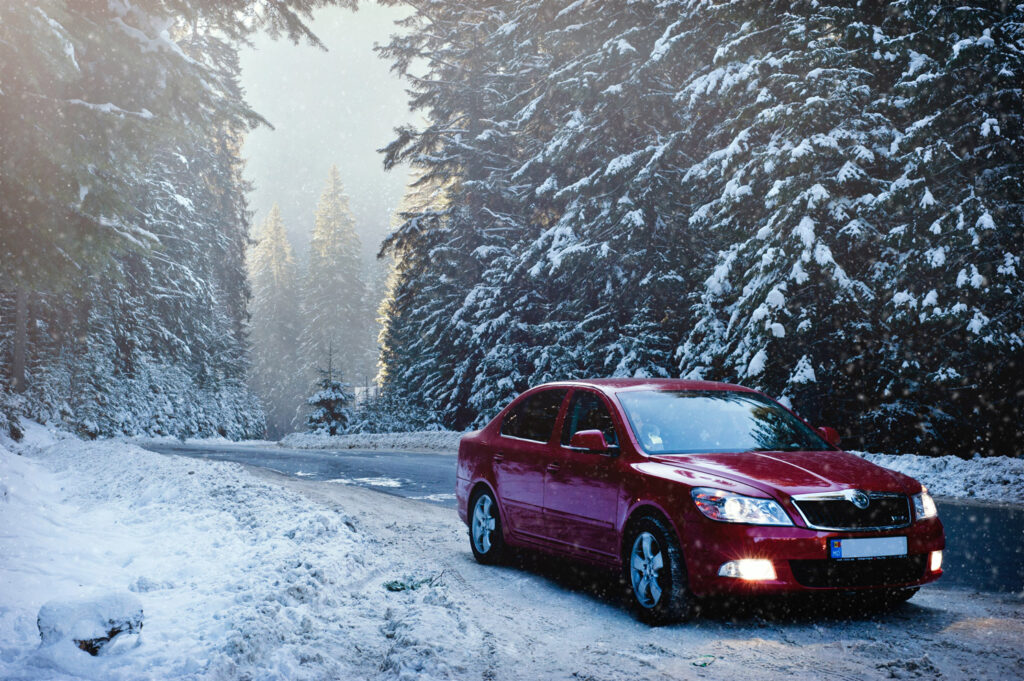Red car sitting on the side of a snow-covered road