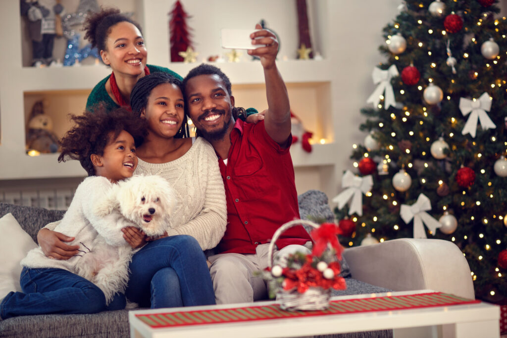 A family of four taking a selfie by a Christmas tree
