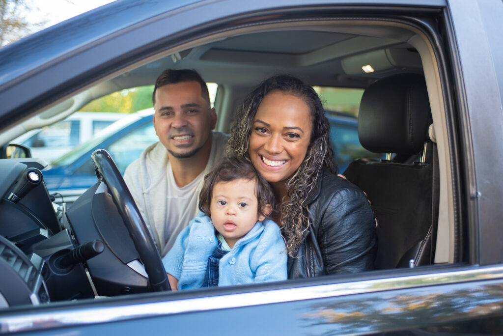Husband and wife with their baby sitting in their new car