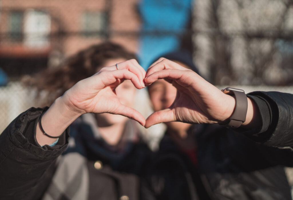 couple standing together and making a heart with their hands