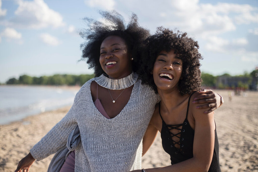 two friends smiling together while on vacation at the beach