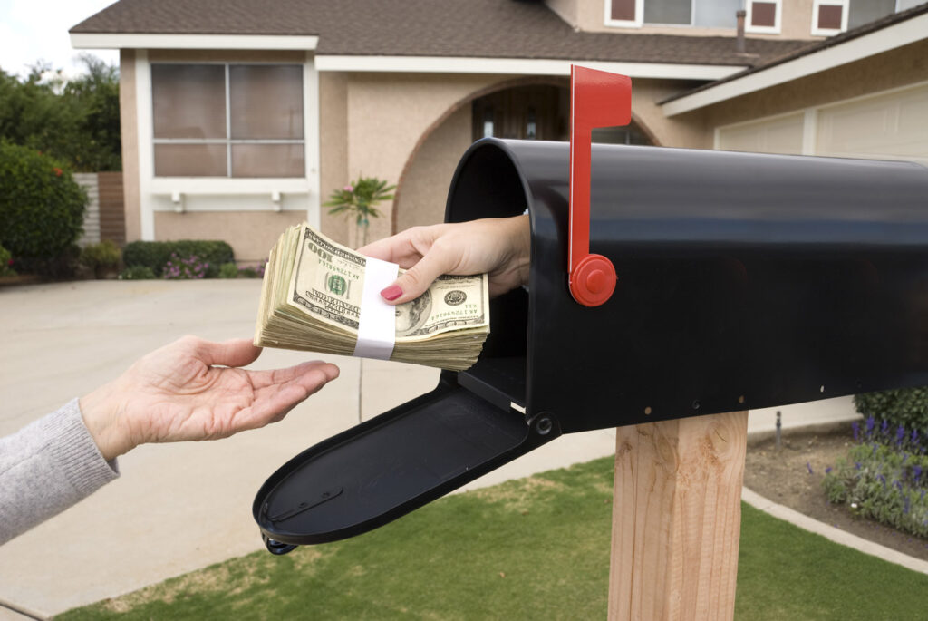 Woman being handed money out of a mailbox.