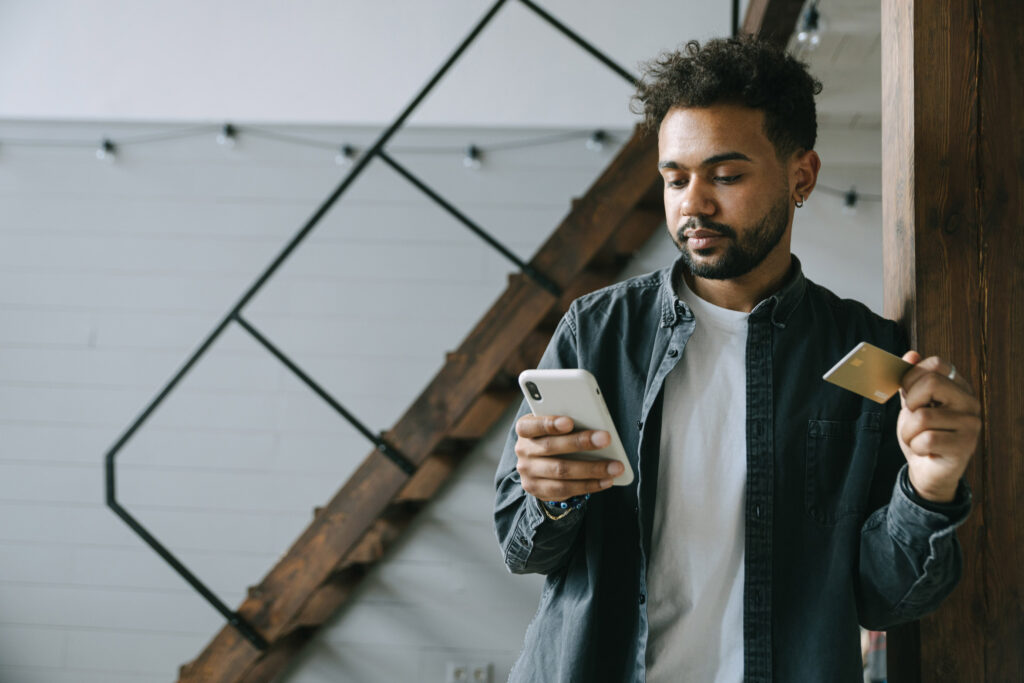Man looking at his cellphone as he holds a credit card