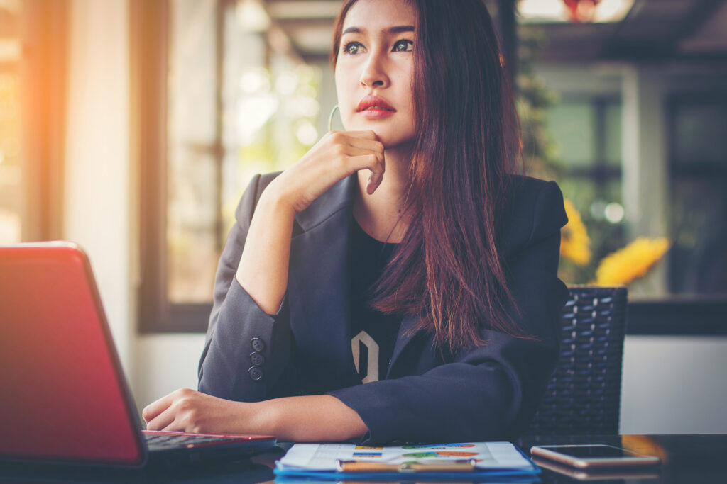 Woman sitting at her desk with a red laptop.