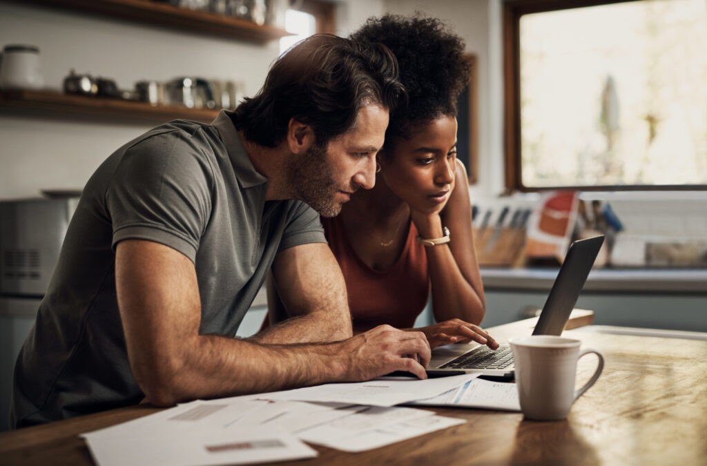 a couple looking at financial documents on a laptop