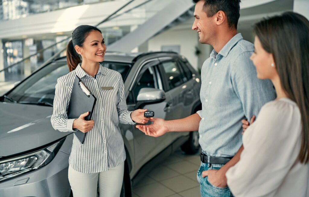 happy couple receiving the keys to their new car from a car saleswoman