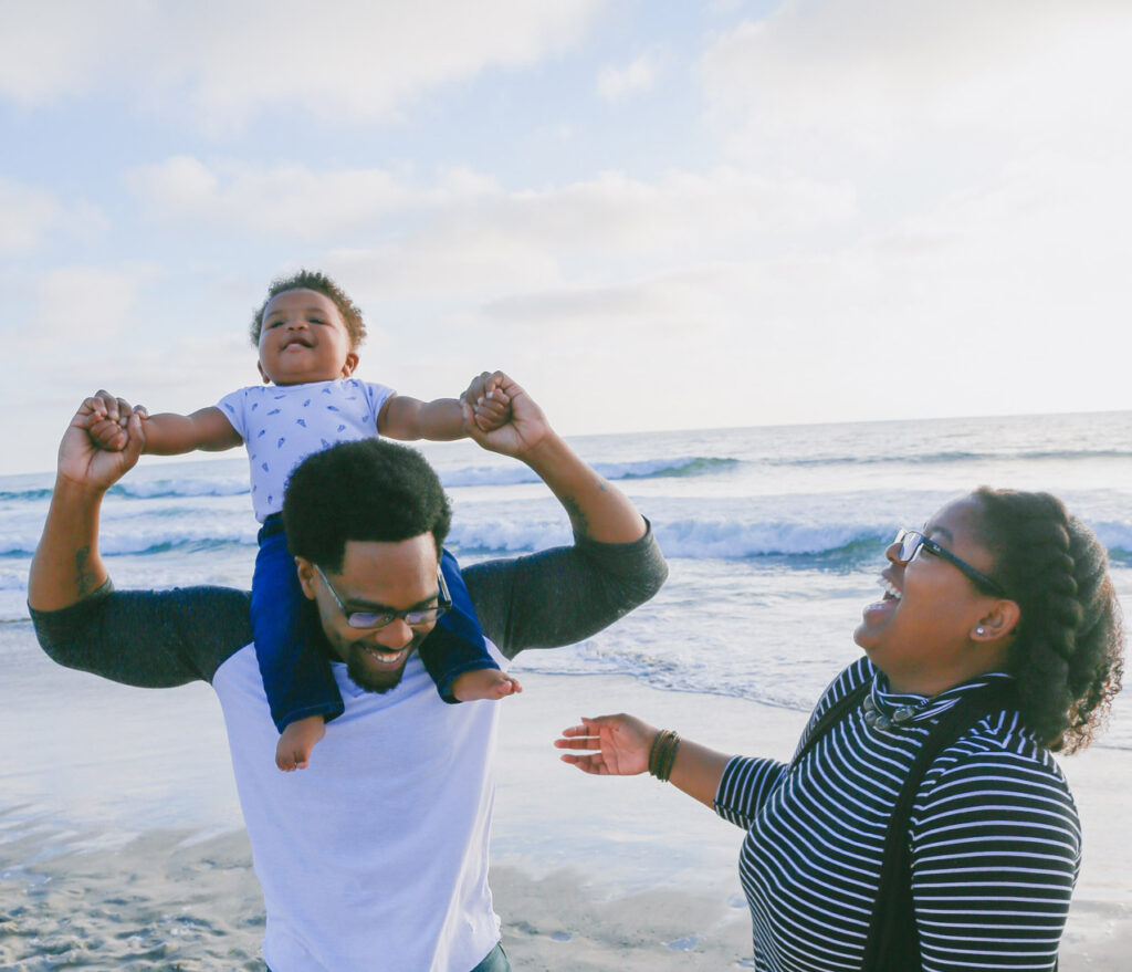 husband and wife with their young son at the beach together