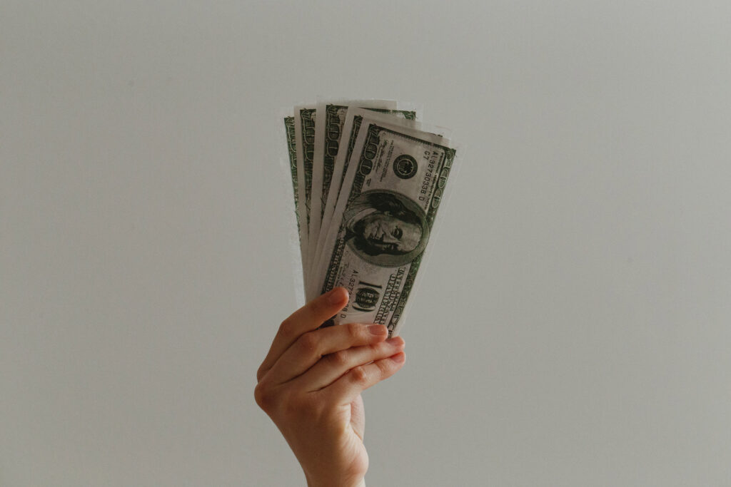 a woman's hand holding four one-hundred dollar bills