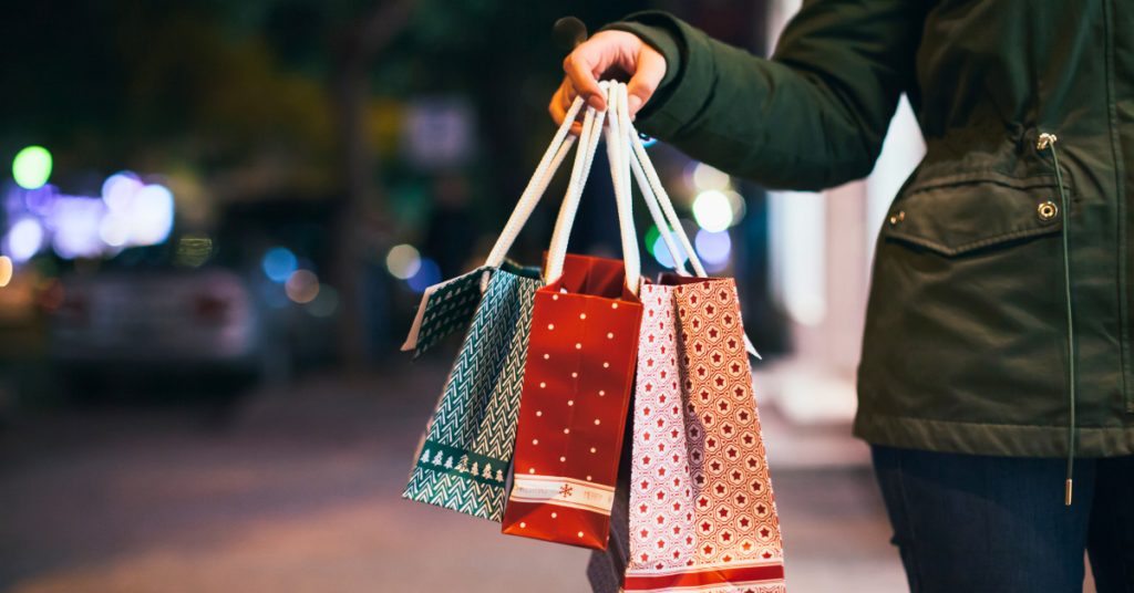 Woman wearing a winter jacket and carrying holiday bags